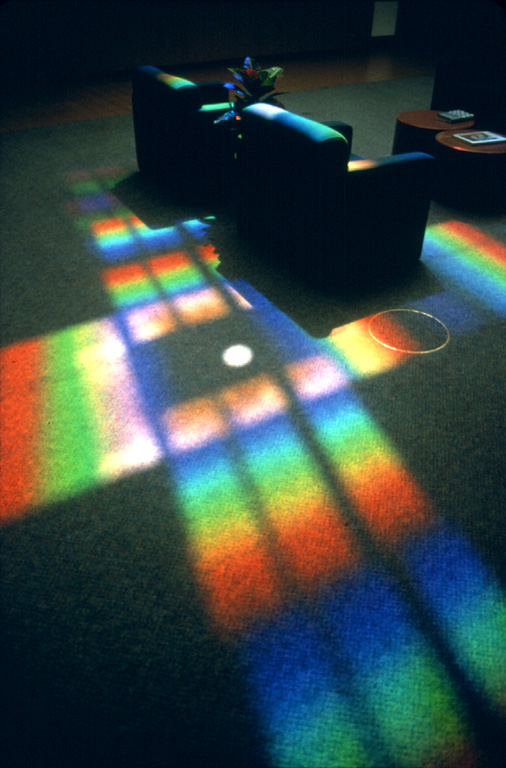 large cross of rainbow light projected on floor by prism